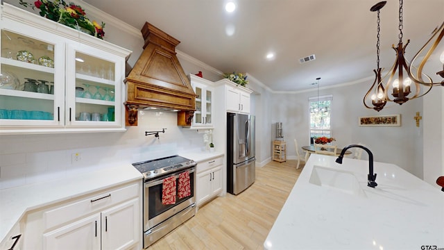 kitchen featuring stainless steel appliances, light hardwood / wood-style floors, white cabinetry, hanging light fixtures, and premium range hood