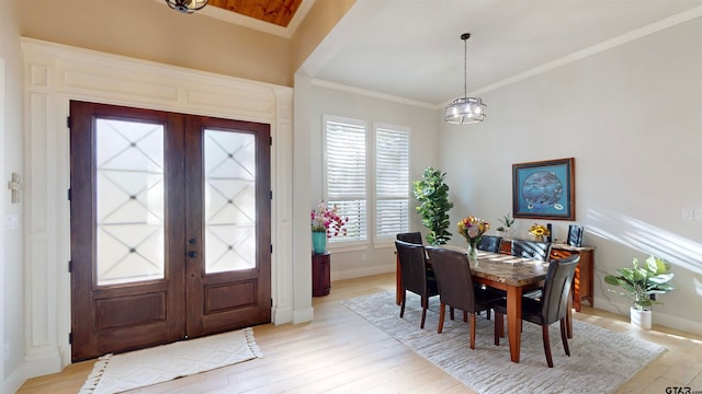 entryway with ornamental molding, a chandelier, french doors, and light hardwood / wood-style floors