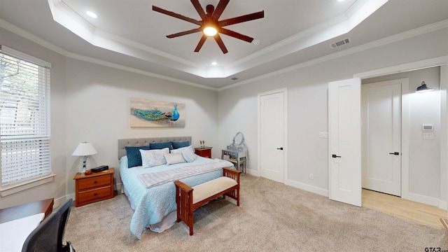 carpeted bedroom with ceiling fan, crown molding, and a tray ceiling