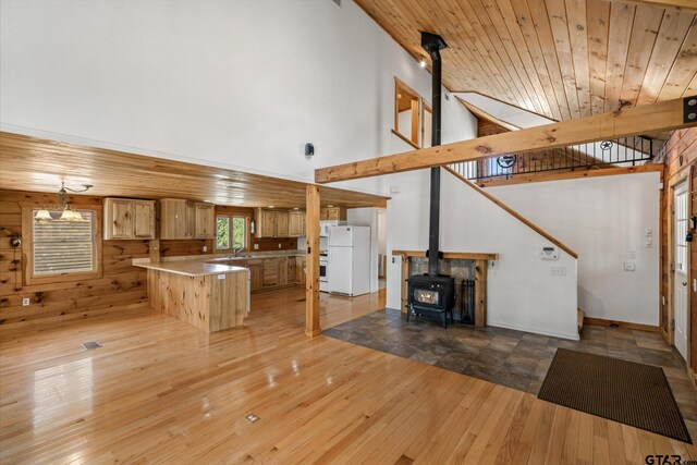 11698 Piper Ln, Frankston, TX 75763 - unfurnished living room featuring a wood stove, light wood-style floors, a towering ceiling, wooden walls, and a sink