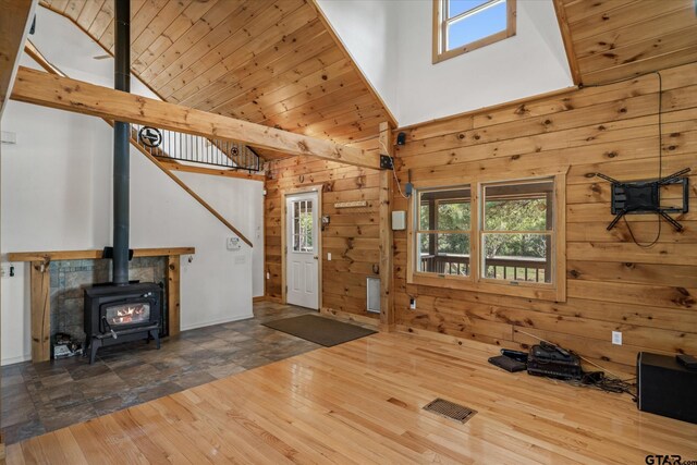 11698 Piper Ln, Frankston, TX 75763 - unfurnished living room featuring high vaulted ceiling, wood walls, healthy amount of natural light, a wood stove, and wood finished floors