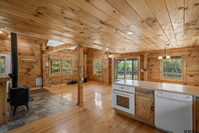 11698 Piper Ln, Frankston, TX 75763 - kitchen featuring white appliances, wood ceiling, wooden walls, light countertops, and a wood stove