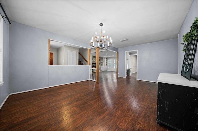 unfurnished dining area featuring visible vents, wood finished floors, stairway, baseboards, and a notable chandelier