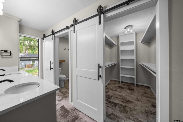 full bathroom featuring a sink, toilet, double vanity, and a spacious closet
