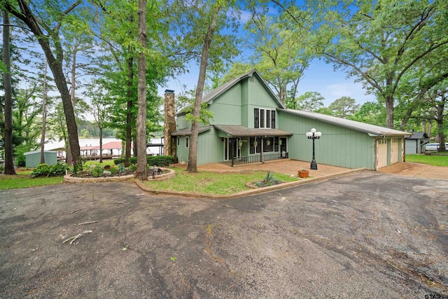 view of front of house featuring a garage, a chimney, and a porch