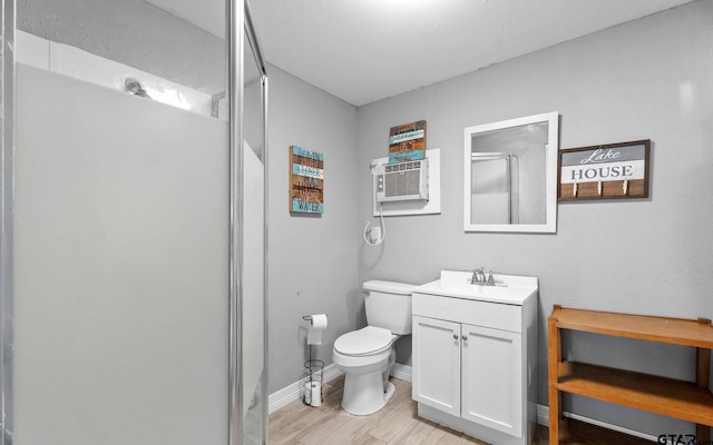 full bath featuring a shower stall, wood finished floors, vanity, baseboards, and toilet