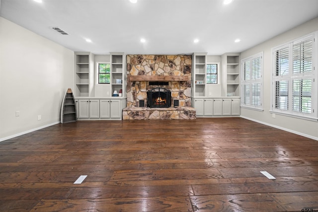 unfurnished living room with visible vents, dark wood finished floors, baseboards, and built in shelves