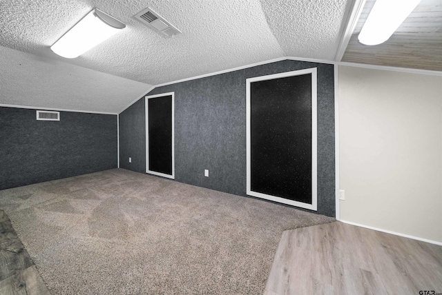 bonus room featuring a textured ceiling, visible vents, and vaulted ceiling