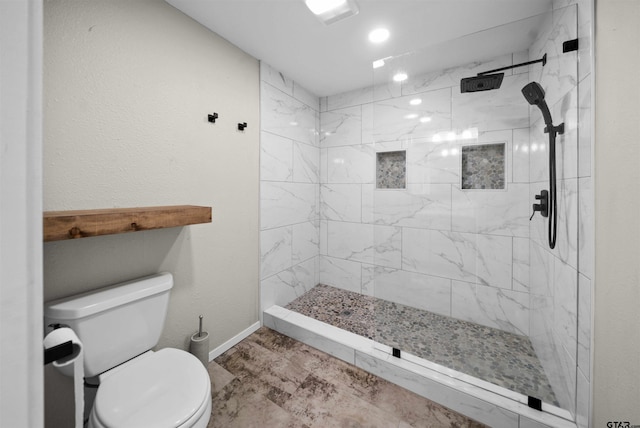 bathroom featuring baseboards, toilet, and tiled shower