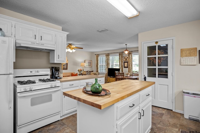 kitchen featuring white appliances, butcher block counters, white cabinets, visible vents, and under cabinet range hood