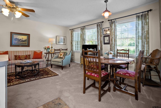 dining room with a ceiling fan, light carpet, and a textured ceiling