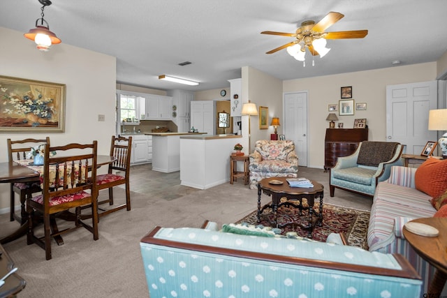living room with ceiling fan, light carpet, and baseboards
