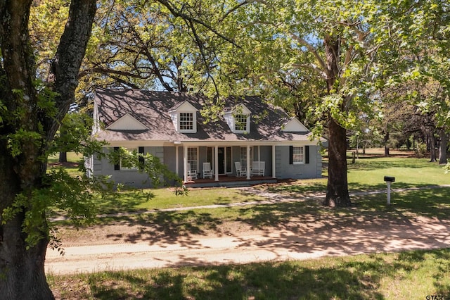new england style home featuring a front yard and covered porch