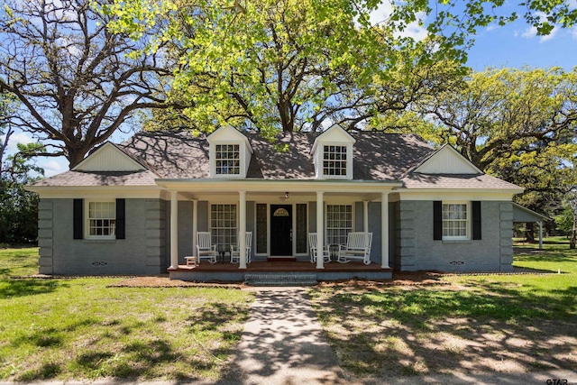 cape cod house featuring a shingled roof, covered porch, and a front yard