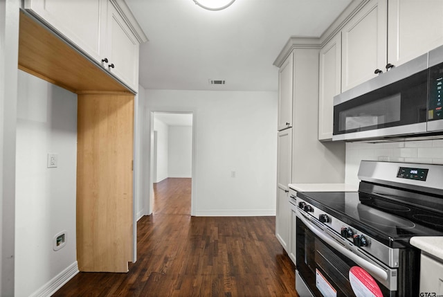 kitchen with decorative backsplash, dark hardwood / wood-style flooring, white cabinets, and appliances with stainless steel finishes