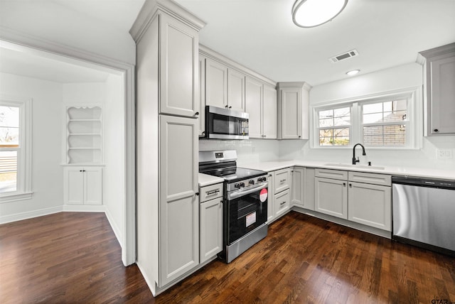 kitchen with sink, tasteful backsplash, built in features, dark hardwood / wood-style floors, and appliances with stainless steel finishes