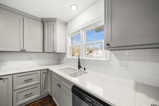 kitchen with gray cabinetry, sink, decorative backsplash, light stone countertops, and dishwashing machine