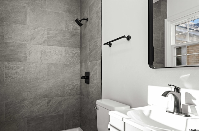 bathroom featuring tiled shower, vanity, and toilet