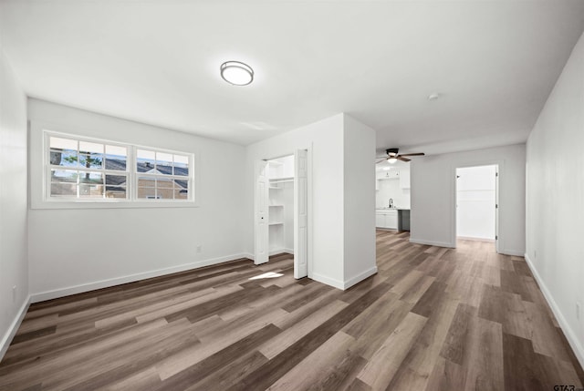 unfurnished living room featuring ceiling fan, dark hardwood / wood-style flooring, and sink