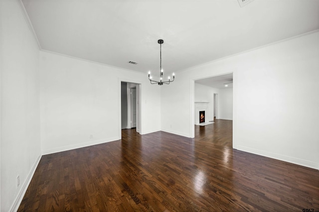 spare room with a notable chandelier, dark hardwood / wood-style flooring, and crown molding