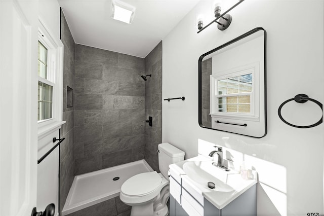 bathroom with vanity, toilet, and tiled shower