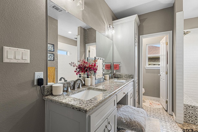 full bath featuring visible vents, a sink, toilet, and double vanity