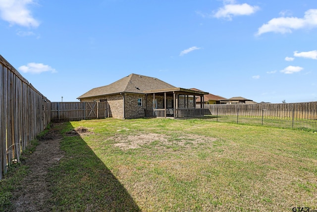 view of yard featuring a sunroom and a fenced backyard