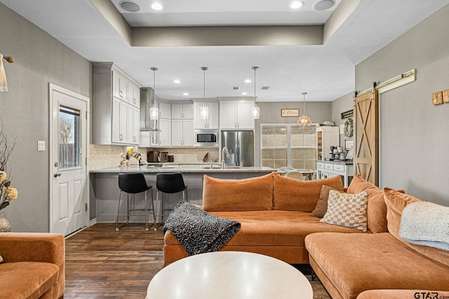 living area featuring dark wood-style floors, a barn door, and recessed lighting
