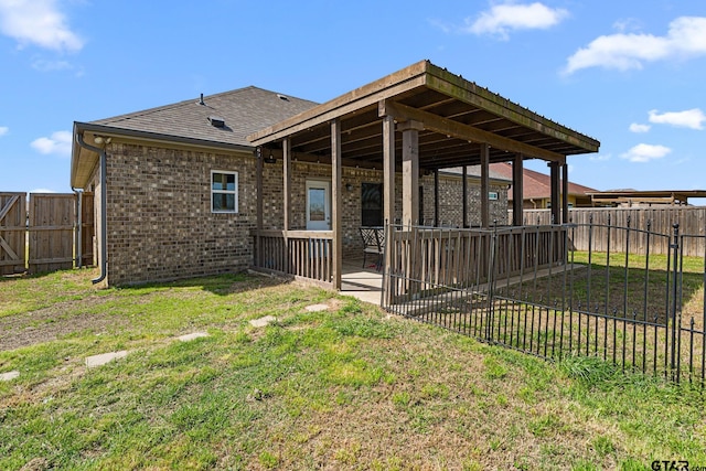 back of property with a fenced backyard, brick siding, a patio area, and a lawn