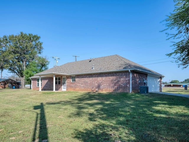 back of property with central AC, a garage, and a yard