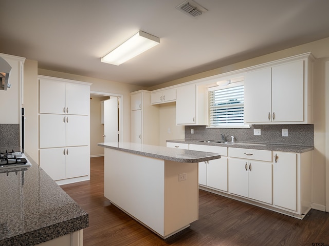 kitchen with sink, dark hardwood / wood-style floors, a kitchen island, white cabinets, and decorative backsplash