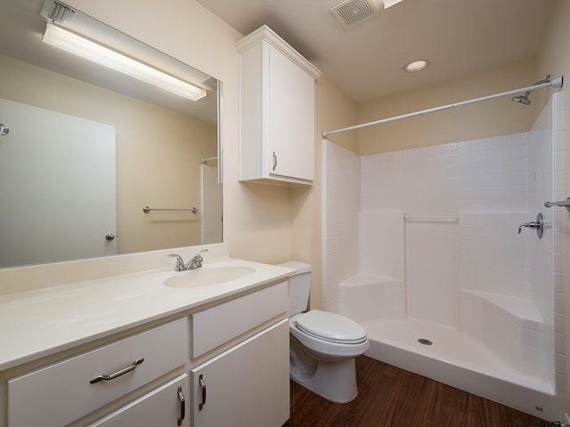 bathroom with toilet, a shower, vanity, and wood-type flooring