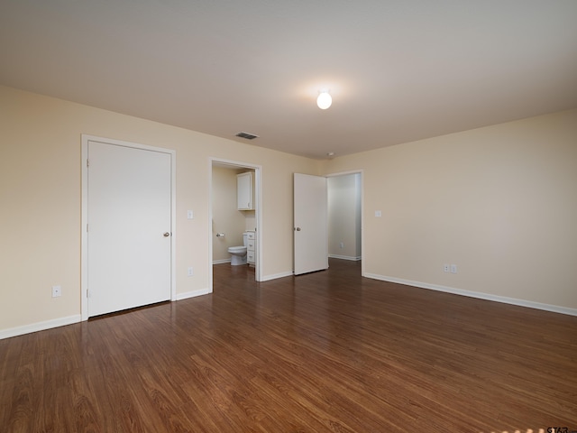 unfurnished bedroom featuring dark wood-type flooring and ensuite bath