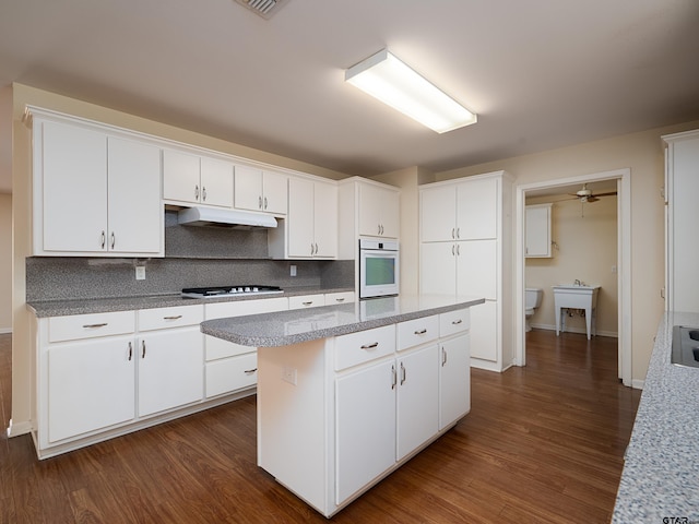 kitchen featuring white cabinets, a center island, dark hardwood / wood-style floors, and oven