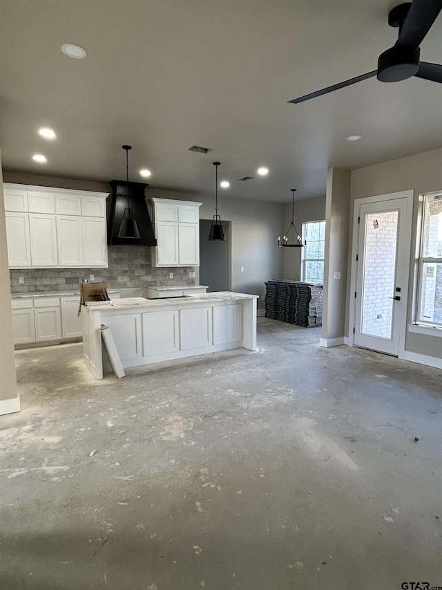 kitchen featuring tasteful backsplash, hanging light fixtures, custom exhaust hood, and white cabinets