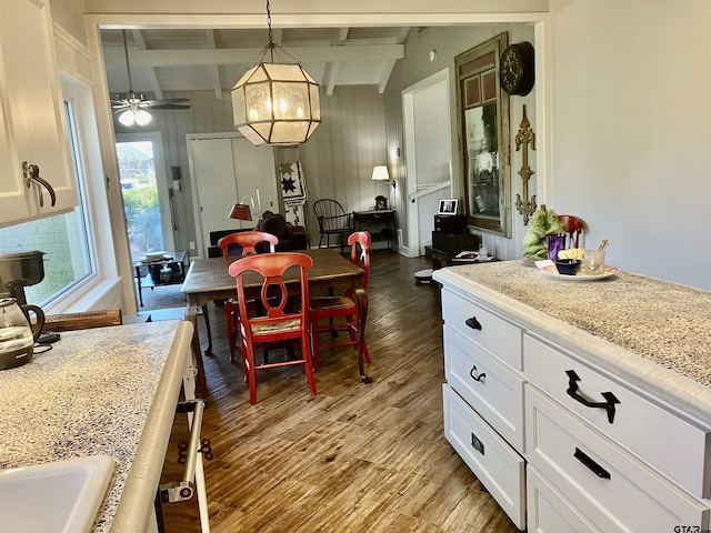 dining area with beam ceiling, ceiling fan, and light wood-type flooring