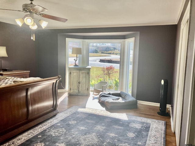 bedroom featuring hardwood / wood-style flooring, ornamental molding, and ceiling fan