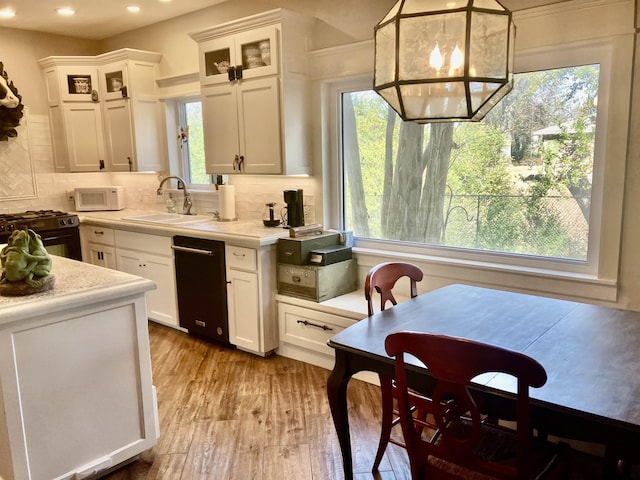 kitchen with hanging light fixtures, light hardwood / wood-style flooring, white cabinets, and black appliances