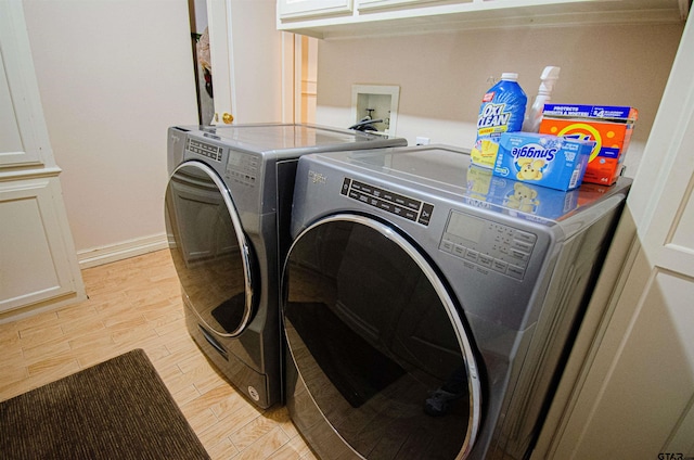 clothes washing area featuring light wood-type flooring, cabinets, and washing machine and dryer