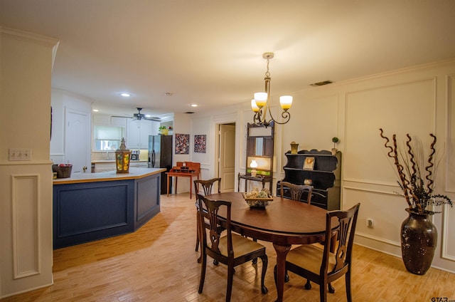 dining space with ceiling fan with notable chandelier, crown molding, and light hardwood / wood-style flooring