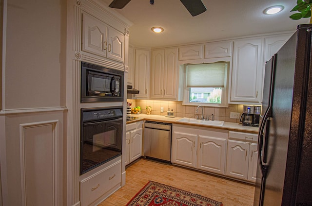 kitchen with black appliances, sink, light hardwood / wood-style floors, and white cabinets