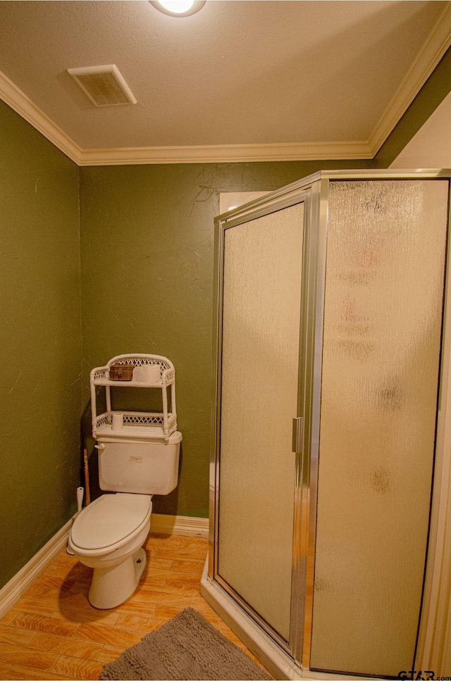 bathroom with hardwood / wood-style flooring, toilet, an enclosed shower, and ornamental molding