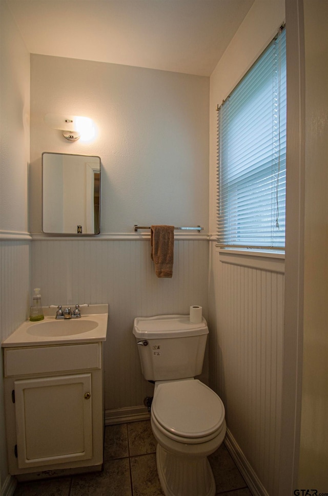 bathroom with vanity, wood walls, tile patterned floors, and toilet