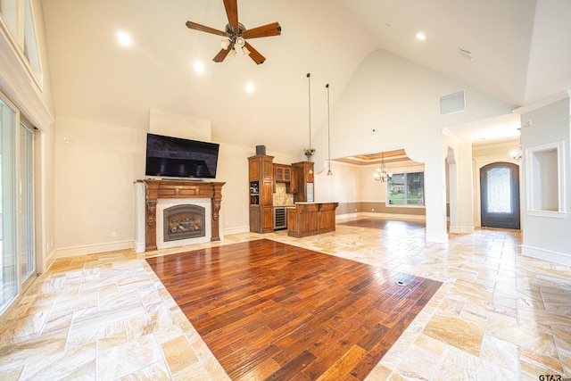 living room with ceiling fan with notable chandelier and high vaulted ceiling