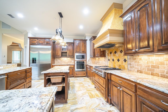 kitchen with backsplash, light stone counters, custom exhaust hood, built in appliances, and hanging light fixtures