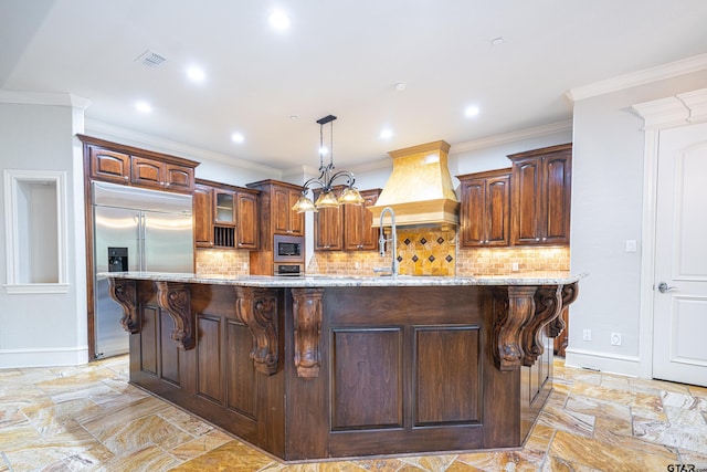 kitchen featuring built in appliances, a large island, custom range hood, and crown molding