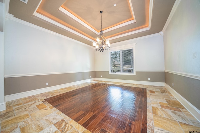 unfurnished room with a chandelier, a tray ceiling, and crown molding