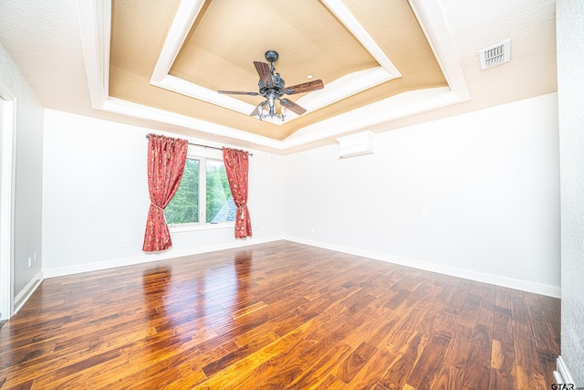 empty room with a tray ceiling, ceiling fan, a textured ceiling, and dark hardwood / wood-style floors