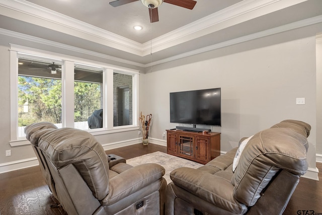 living area with baseboards, ceiling fan, a tray ceiling, ornamental molding, and dark wood-style flooring