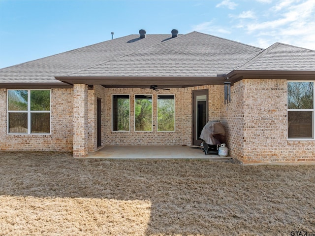 back of property with a ceiling fan, a patio area, brick siding, and a shingled roof